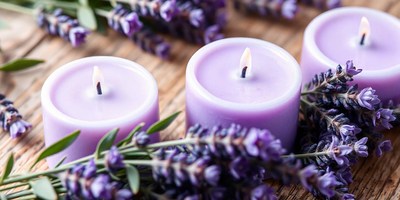 Three purple candles are arranged on a wooden surface