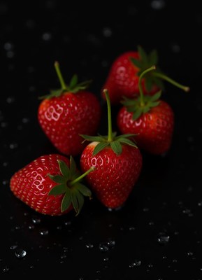 Five red strawberries on a black background