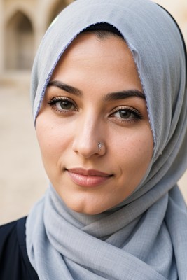 A woman wearing a light blue hijab looks at the camera