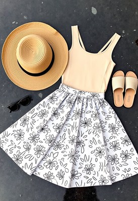 Floral skirt, beige top, and straw hat on gray