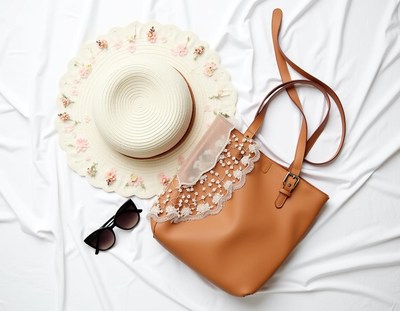 Straw hat, tote bag, and sunglasses on white surface