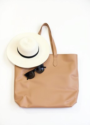 A tan leather tote bag lays flat on a white surface