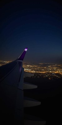 A plane wing in flight over a city at night