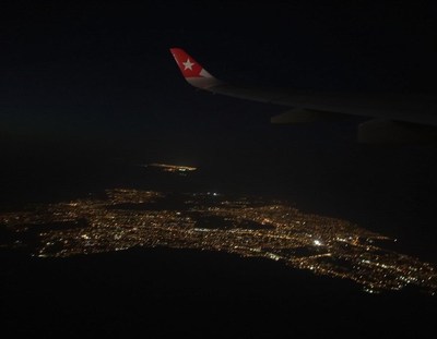 A city lights up the night from a plane window