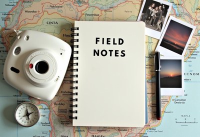 A field notebook, camera, and compass lie on a map