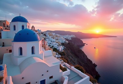 White church with blue domes atop a cliff at sunset