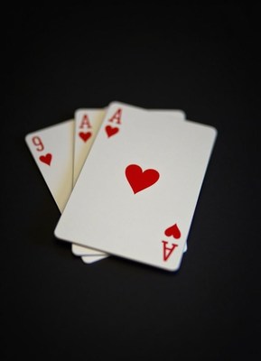 Three aces of hearts lie on a black surface