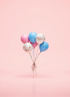 A bunch of colorful balloons stand on a pink background