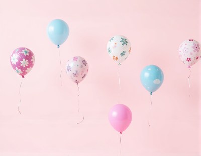 Colorful balloons float against a pink background