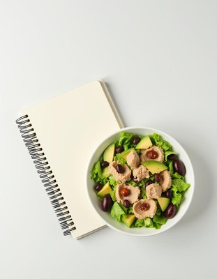 Healthy salad with notebook on white table