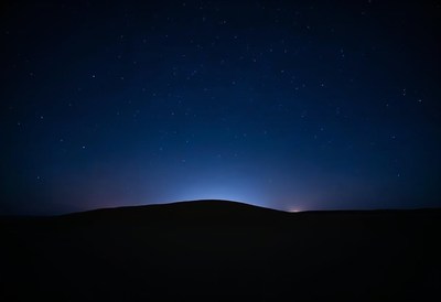 Night sky over a distant horizon illuminated by stars