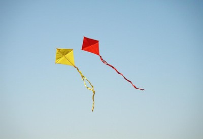 Colorful kites soar in a clear blue sky during a sunny day