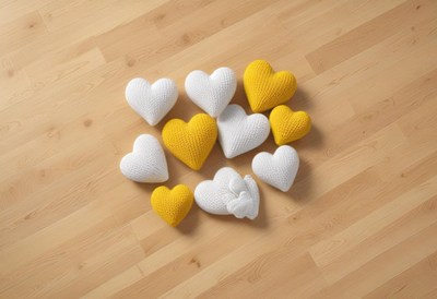 Decorative knitted hearts arranged on wooden floor