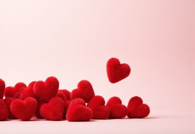 Red fuzzy hearts scattered on a soft pink background