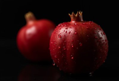 Two Dewy Pomegranates on Black Background