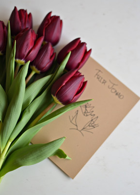 Beautiful red tulips with a handwritten note on table