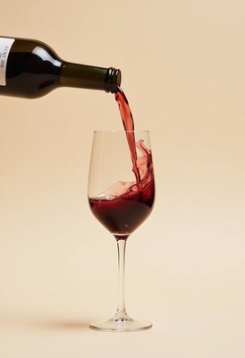 Pouring red wine into a glass against a plain background