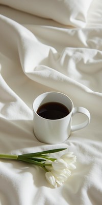 Cozy morning coffee with fresh flowers on soft bedding