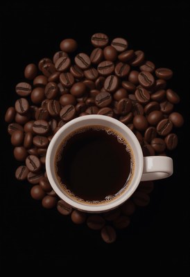 Rich coffee surrounded by roasted beans on dark background