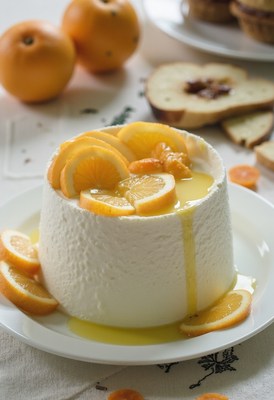 Creamy dessert topped with citrus fruits in sunny kitchen