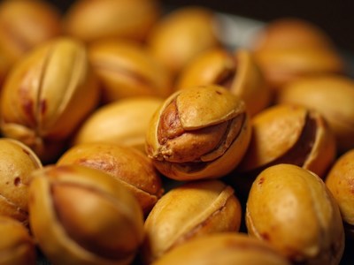 Pile of roasted nuts with cracked shells displayed close-up
