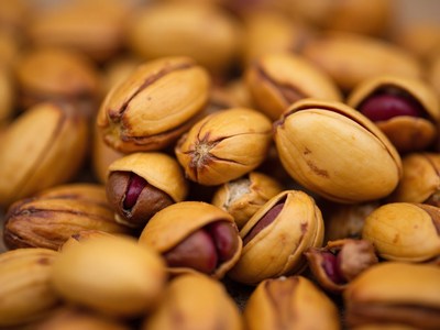 Pistachios in their textured shells on a wooden surface