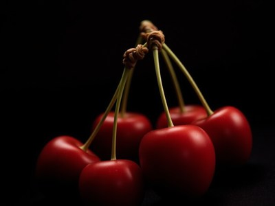 Red cherries suspended with twine against a dark background
