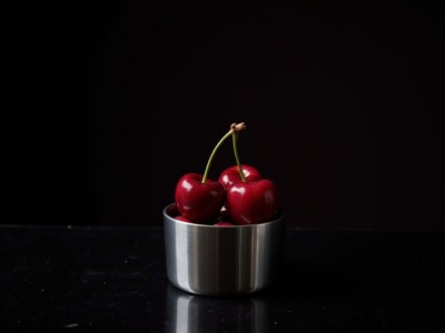 Fresh cherries in a silver bowl on a dark surface