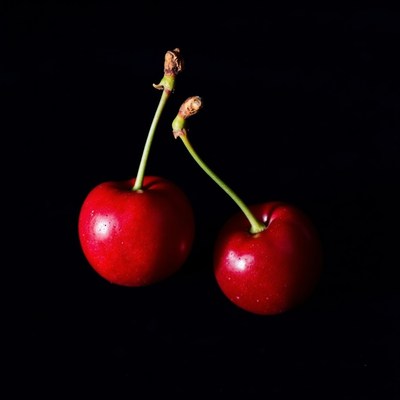 Bright red cherries illuminated against a dark background