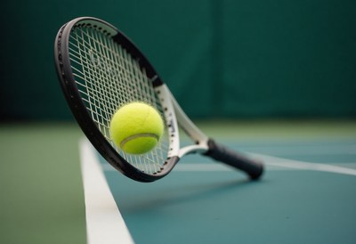 Tennis ball bouncing on court with racquet nearby