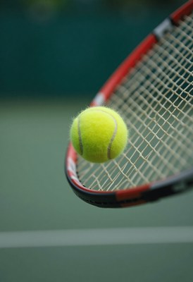 Tennis ball in mid-air near racket during afternoon play