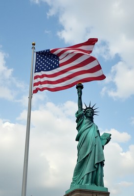 Statue of liberty stands tall with american flag waving