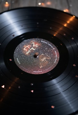 Vinyl record with glitter on wooden table