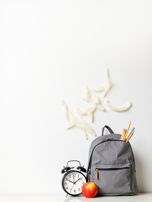 School supplies and clock on a clean table setting