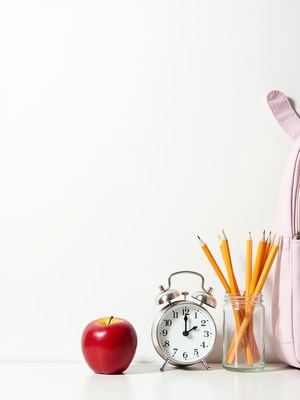 School supplies arranged with apple and clock on desk