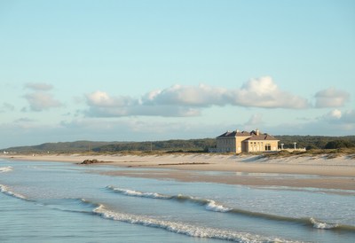 Cozy coastal house beside gentle waves at sunset