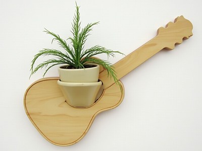 Guitar-shaped wall planter with green plant decoration