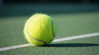 Bright yellow tennis ball on green court surface