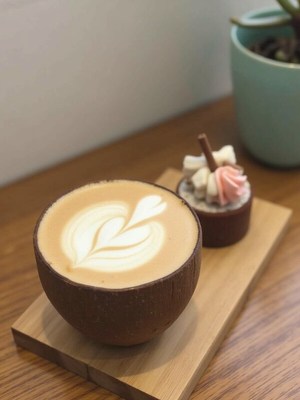 Coffee served in a coconut bowl with dessert on the side