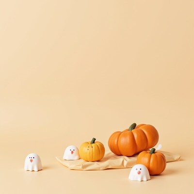 Decorative pumpkins and ghost figures on light background