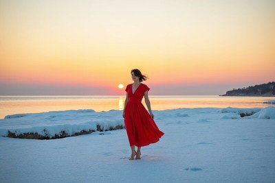 Woman in red dress on snowy beach at sunset