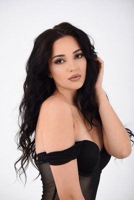 Woman posing in elegant black dress with soft curls