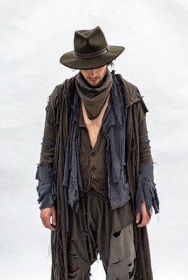 Man in tattered clothing stands against a light background