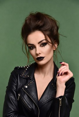 Woman poses confidently in leather jacket with bold makeup