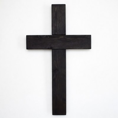 Simple black wooden cross on white wall background