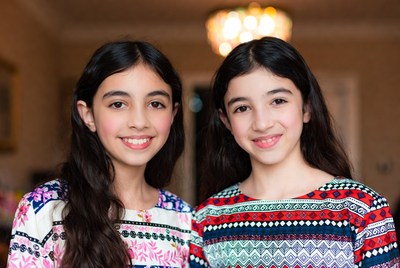 Twin sisters smiling together in a cozy indoor setting