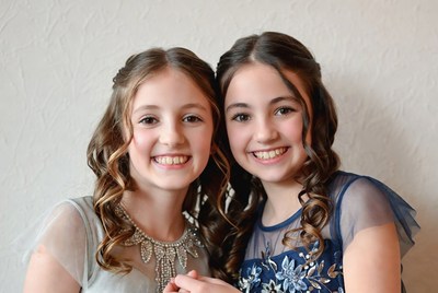 Two smiling girls in elegant dresses at a celebration