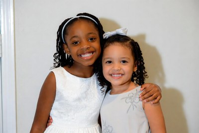 Two smiling girls posing in elegant dresses indoors