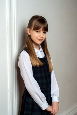Young girl in school uniform poses confidently indoors