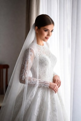 Bride standing by the window in elegant white dress